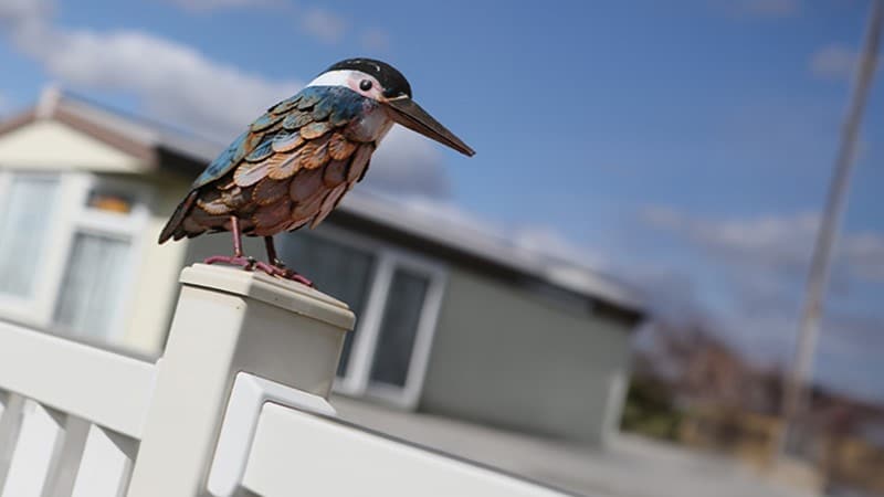 a wooden kingfisher bird sat on top of a wooden post