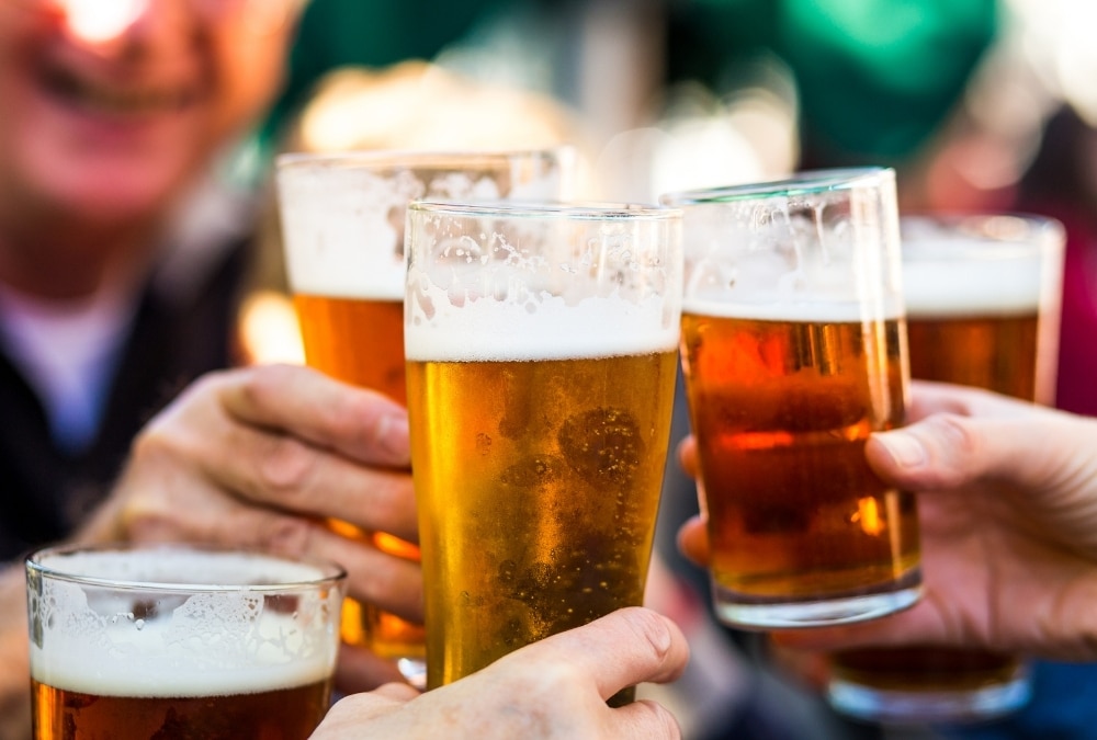 Two pints of lager on a red outdoor table at a pavement bar