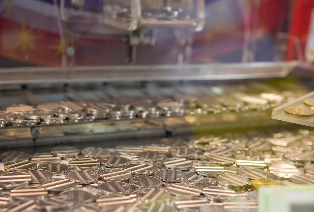 Close-up of silver coins and tokens inside an arcade coin pusher machine