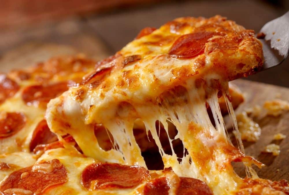 Slice of pepperoni pizza being lifted with gooey melted cheese at Fantasy Island Skegness theme park