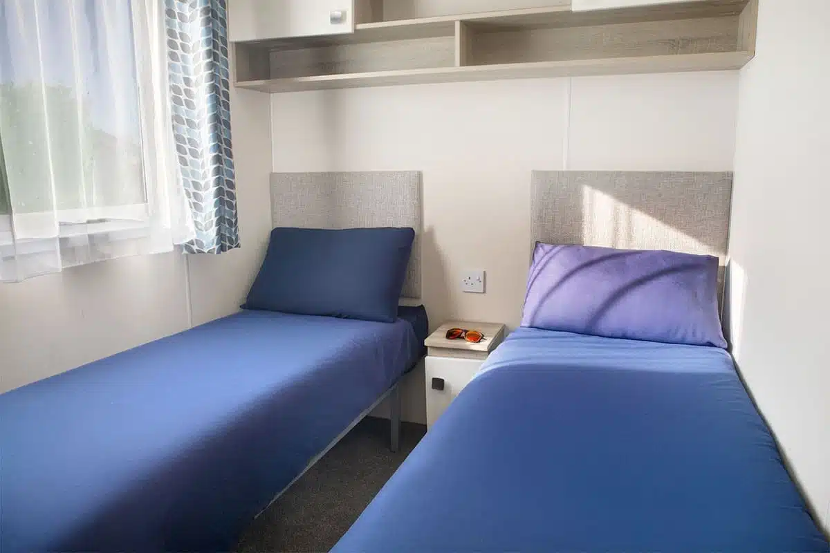 Guest bedroom in Premium Plus 3 Bedroom Caravan with two single beds, providing a comfortable space for family or friends