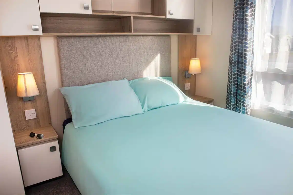 Master bedroom in Premium Plus 3 Bedroom Caravan with a comfortable double bed and ample storage for a relaxing retreat.