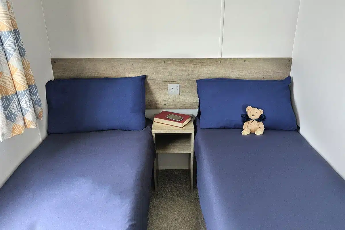 Guest bedroom in a Standard 3 Bedroom Caravan with two single beds, perfect for accommodating family or friends.
