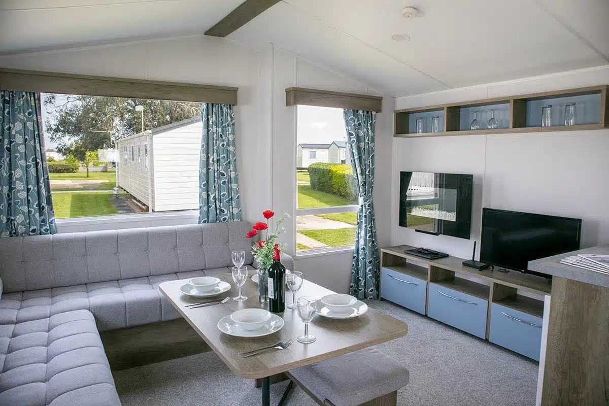 Living room in a Standard 3 Bedroom Caravan, featuring a Smart TV and dining table, perfect for family relaxation.