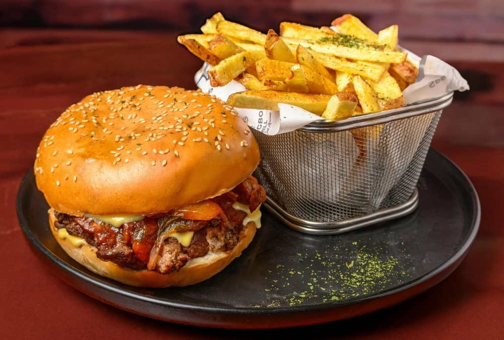 Cheeseburger in a sesame bun with chunky chips in a metal basket