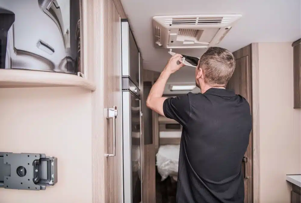 A maintenance worker fixing the air-con within a static caravan