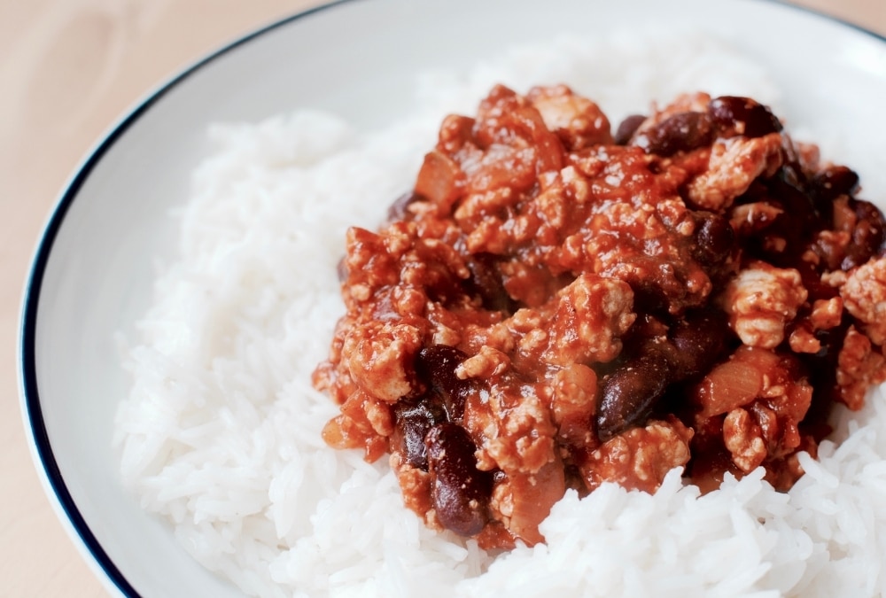 Bowl of chilli con carne with kidney beans served over rice, an easy one-pan caravan dinner