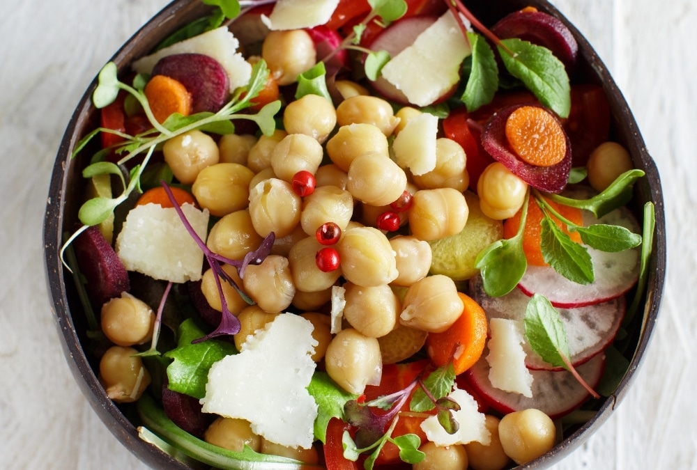 Bowl of Greek chickpea salad with feta, radish, carrot and microgreens, a no-cook caravan lunch idea