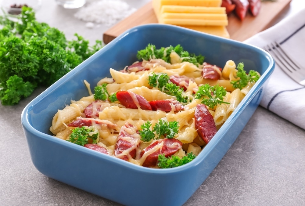 Sausage and pasta bake topped with melted cheese and parsley in a baking dish