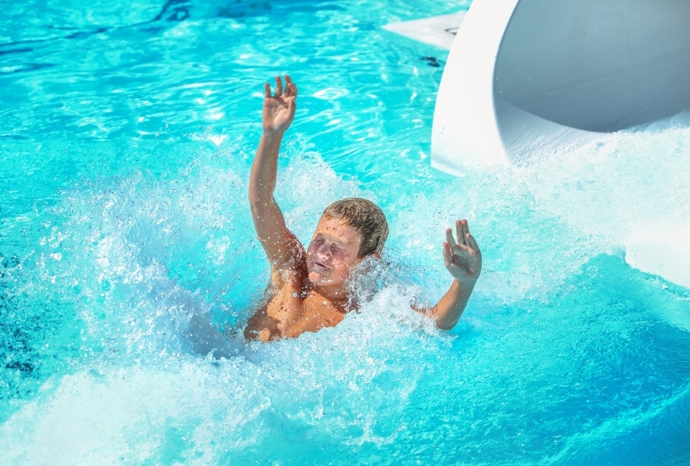 Boy splashing into the pool after a water slide at Butlin's Splash Waterworld, Skegness
