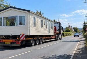 Static caravan being transported on a low loader lorry along a UK road